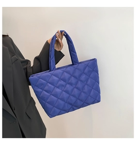Detailed view of the large quilted tote bag with diamond pattern and padded handle