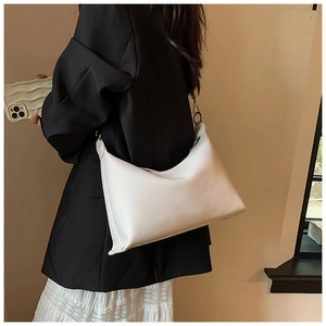 Dettaglio di una borsa hobo in pelle bianca con fibbie argentate indossata da una modella