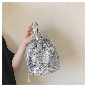 Détail d'un sac seau à paillettes argentées avec cordon et texture brillante de soirée