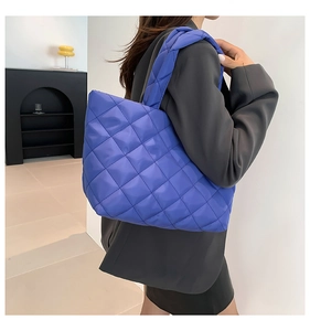 Close-up of a bright purple quilted puffer tote bag shown on a model's shoulder