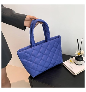 Detailed shot of dark blue quilted nylon tote bag with puffy texture and handle