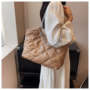 Detail view of quilted puffer tote bag in beige PU leather with silver chain strap