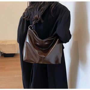 Detail of dark brown tote bag with high-gloss finish and silver metal ring hardware