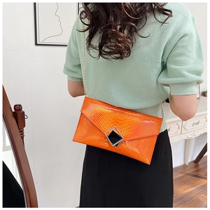 Dettaglio pochette arancione lucida con trama a coccodrillo e chiusura in metallo argento