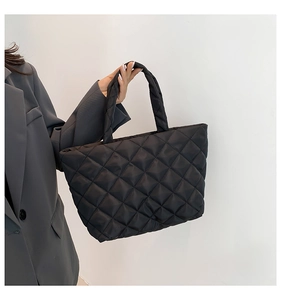 Close-up of black quilted diamond pattern on large casual tote bag with padded texture