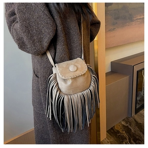 Detailed view of suede crossbody bag with long fringes and decorative braided stitching