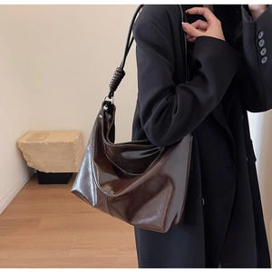Detailed close-up of dark brown hobo bag featuring a unique twisted knot strap design