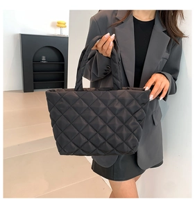 Detailed macro view of black quilted tote bag with rhombus pattern and modern design
