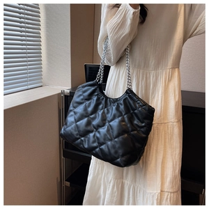 Classic black quilted tote bag with silver chain straps shown on a model