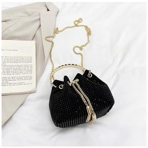 Détail du sac seau noir en strass avec poignée dorée et cordon à pompon élégant