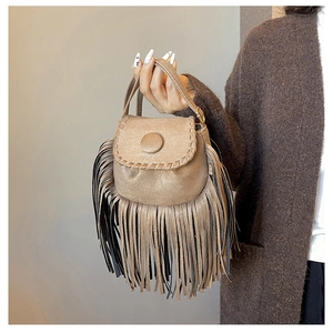 Detailed view of bohemian faux suede saddle bag with fringe tassels and woven edge