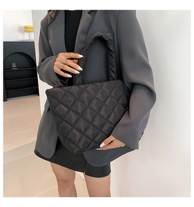 Close-up of quilted black tote bag with diamond stitching texture and padded handle