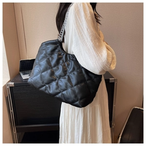 Detail view of black quilted hobo bag with classic diamond stitching and silver chain strap