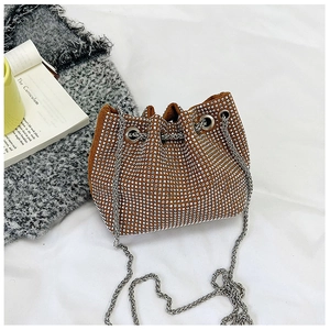 Détail d'un sac seau marron à strass avec chaîne argentée et fermeture à cordon