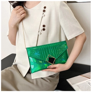 Fashionable green croc-embossed leather clutch bag with golden chain shown on a model