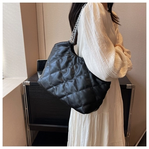 Close-up of black quilted tote bag with silver chain straps shown on a model