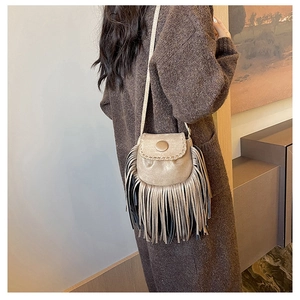 Detail of vintage suede saddle bag with fringe tassels and circular button closure