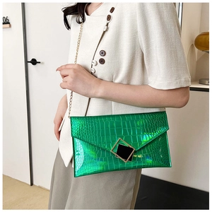 Detail showing bright green crocodile texture clutch with gold chain and black buckle