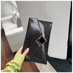 Dettaglio pochette nera con trama a coccodrillo, fibbia argento e catenella dorata