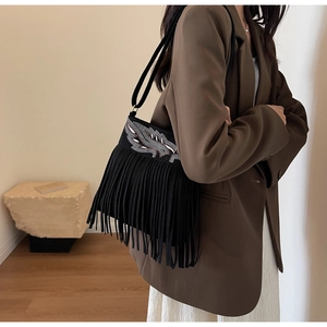 Détail du sac bohème en daim noir avec sequins en forme d'ailes argentées et longues franges