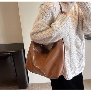 Detail of caramel brown glossy leather tote bag featuring double stitching and large capacity