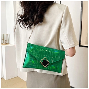 Detail of green crocodile texture envelope clutch bag with gold chain and metal buckle