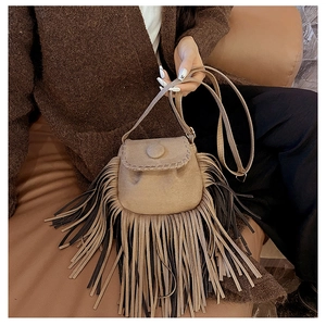 Close-up of brown suede saddle bag with long fringe tassels and warm autumn aesthetics