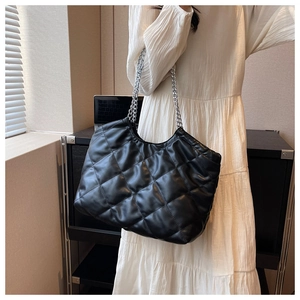 Close-up of quilted black leather chain bag on model with silver metal straps