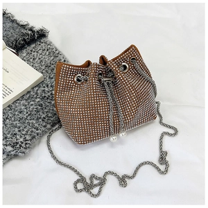 Détail du sac seau en strass avec cordon en perles et chaîne argentée sur tissu texturé