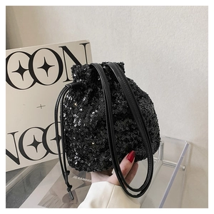Détail d'un sac seau noir à paillettes avec cordon de serrage et poignées en cuir