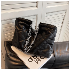 Close-up of black quilted chain bag with diamond stitching and silver metal hardware