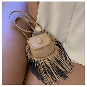 Detailed view of bohemian faux suede saddle bag featuring stylish two-tone long fringe