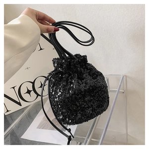Détail d'un sac seau à paillettes noires avec texture réfléchissante et cordon cuir