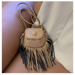 Detail view of suede saddle bag featuring long tassels and rustic stitch edging