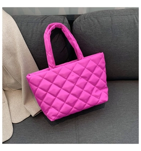 Detail view of pink quilted tote bag with diamond pattern on a grey fabric sofa