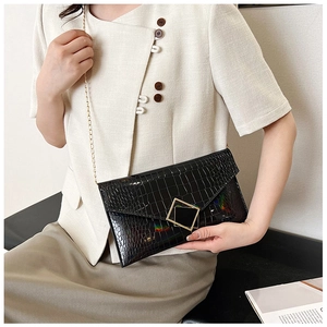 Detail of black crocodile texture envelope bag with gold hardware and chain strap
