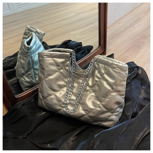 Detail of silver metallic quilted tote bag with diamond stitching and chain straps
