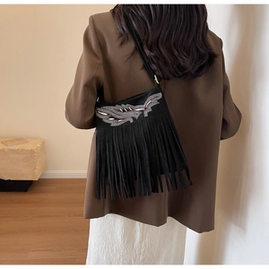 Détail du sac seau noir avec broderie pailletée et longues franges bohèmes