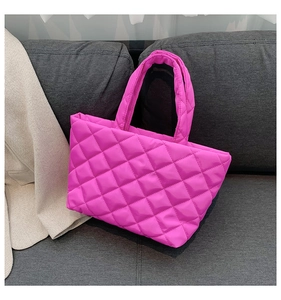 Detail of hot pink quilted puffer tote bag with diamond pattern on grey sofa