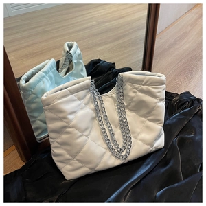 Detail of white quilted tote bag with silver chain straps and elegant rhombic pattern