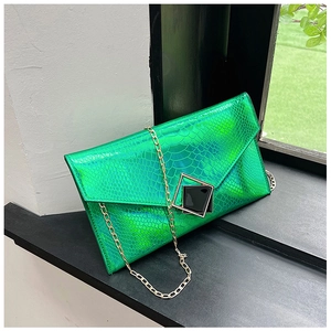 Dettaglio macro della pochette a busta verde smeraldo con trama a serpente e finitura laser