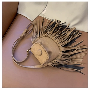 Detail of vintage suede saddle bag with fringe tassels and woven edge stitching