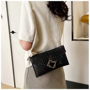 Detail of black stone texture envelope bag with gold square buckle and chain strap