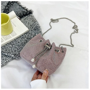 Détail du sac seau en strass rose avec chaîne argentée et perles sur le cordon de serrage