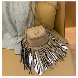 Detailed close-up of bohemian suede saddle bag featuring long bicolor tassels on a seat