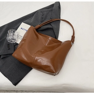 Detail of a brown PU hobo bag featuring knotted shoulder straps and premium stitching
