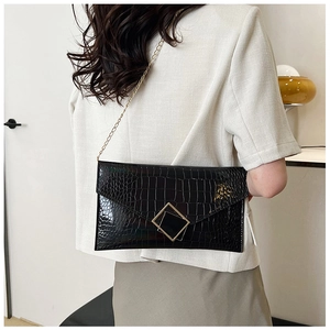 Detail of black crocodile texture envelope bag with gold hardware on a professional model