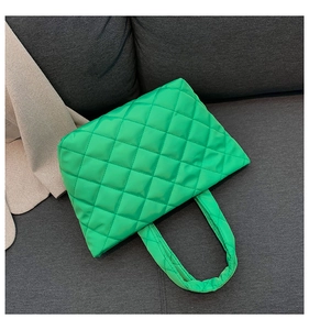 Detailed top view of bright green quilted tote bag with diamond stitching on sofa