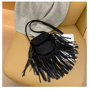 Detail of a black suede crossbody bag with long fringes and flap closure on a chair