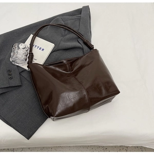 Detail view of dark coffee leather shoulder bag featuring a unique knotted handle design